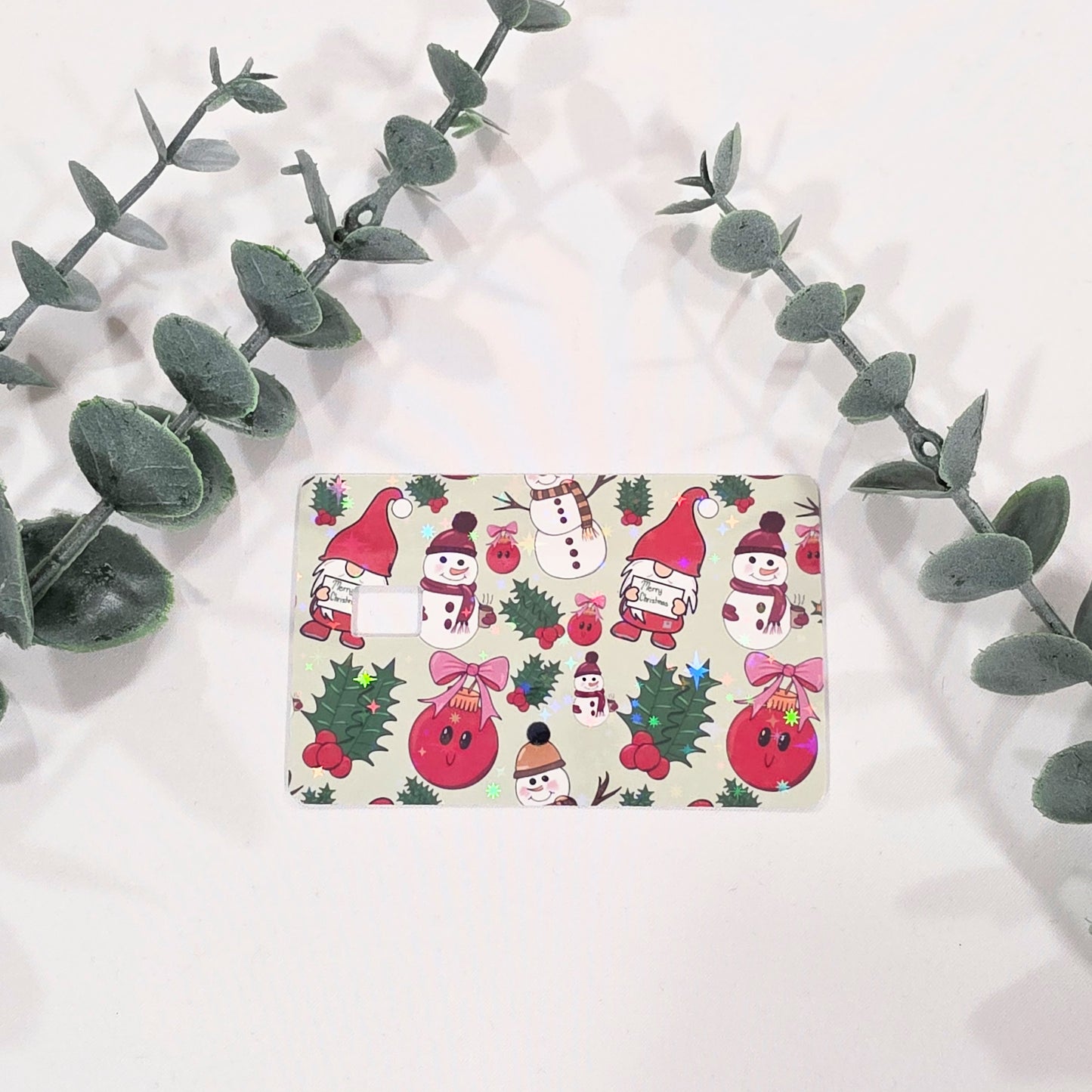 card skin sticker with Christmas-themed design featuring gnomes, snowmen, and holly leaves on a white background.