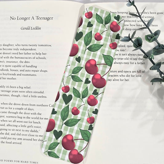 Book with a decorative bookmark featuring cherries and a green checkered pattern on an open book.