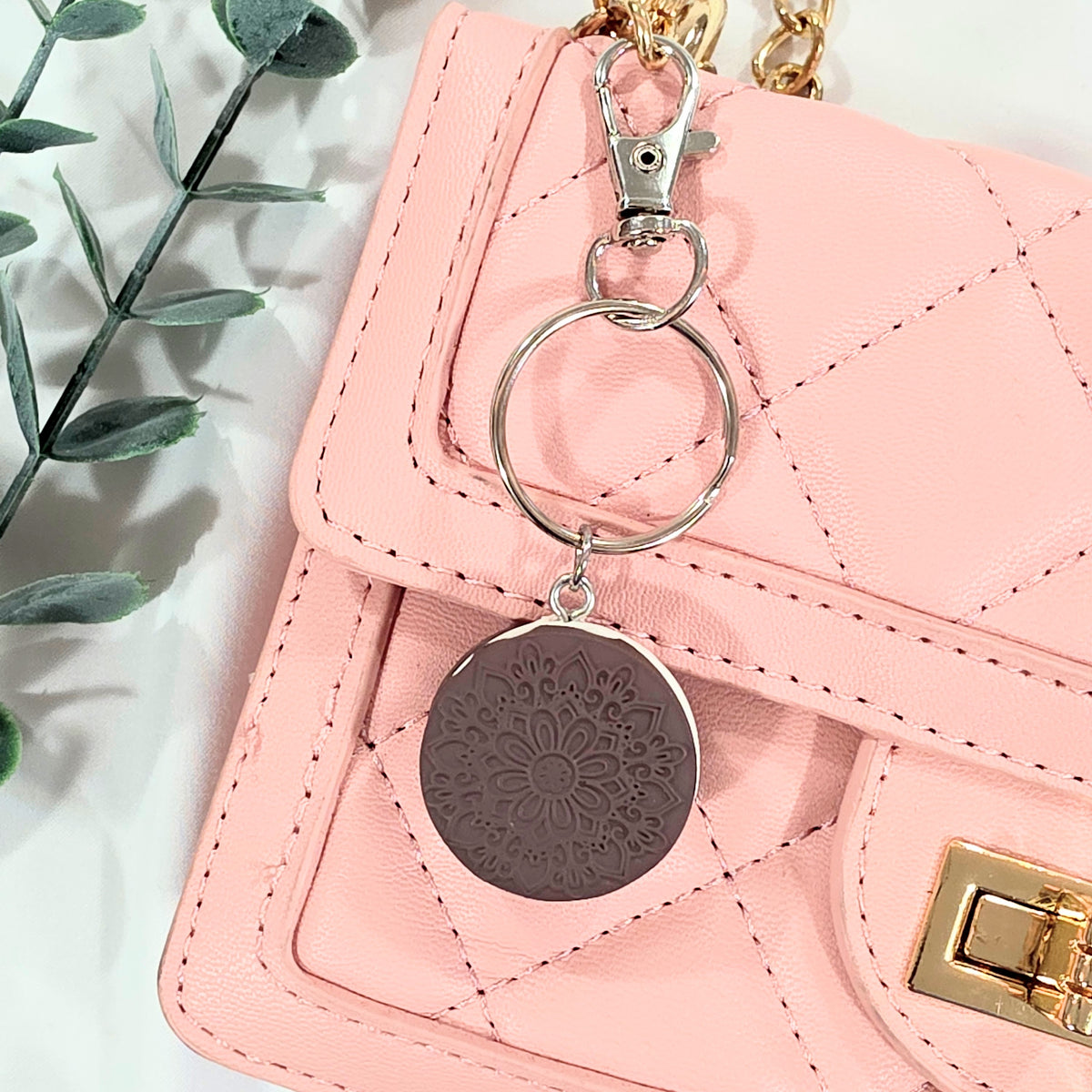 Pink handbag with a cookie keychain featuring a floral design on a light background