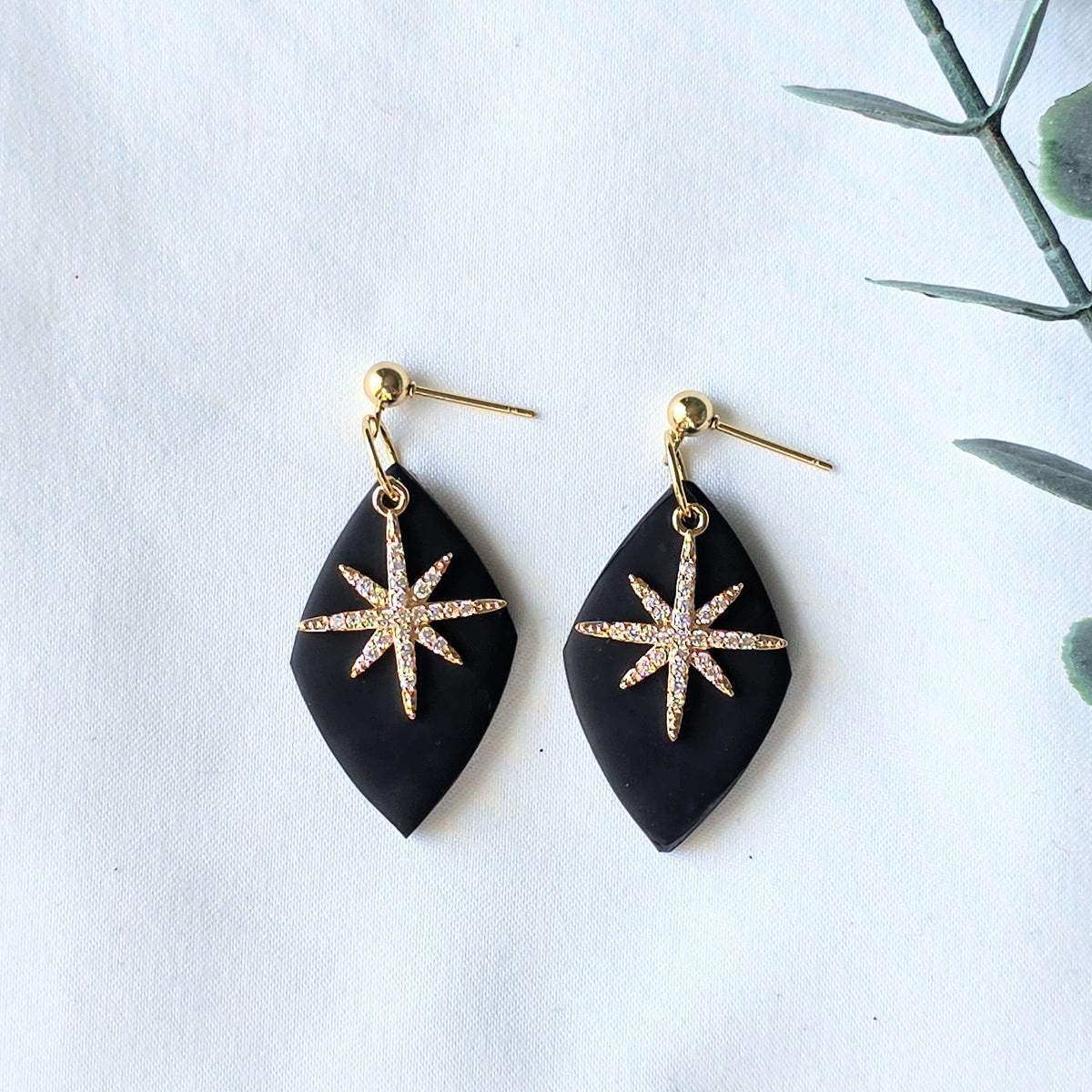 Black earrings with gold star designs on a white background
