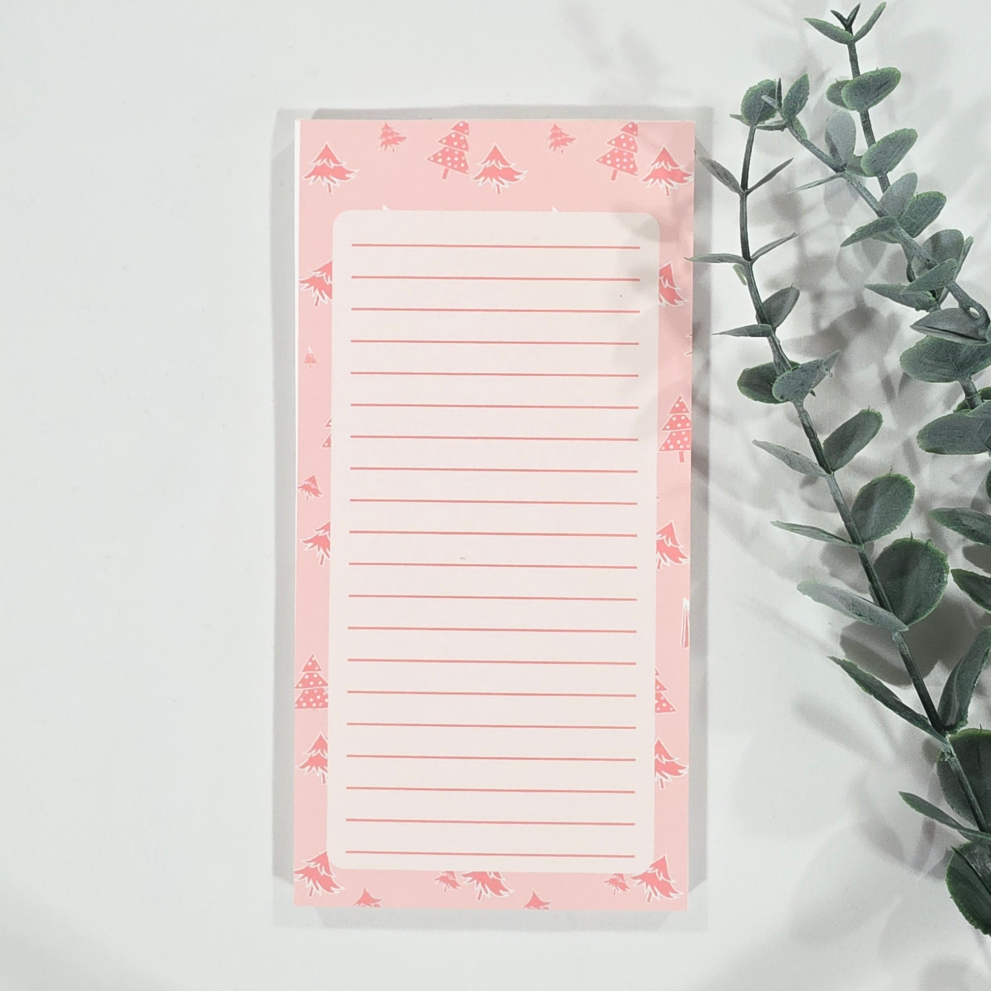 Notepad with christmas tree border on a white background with green leaves