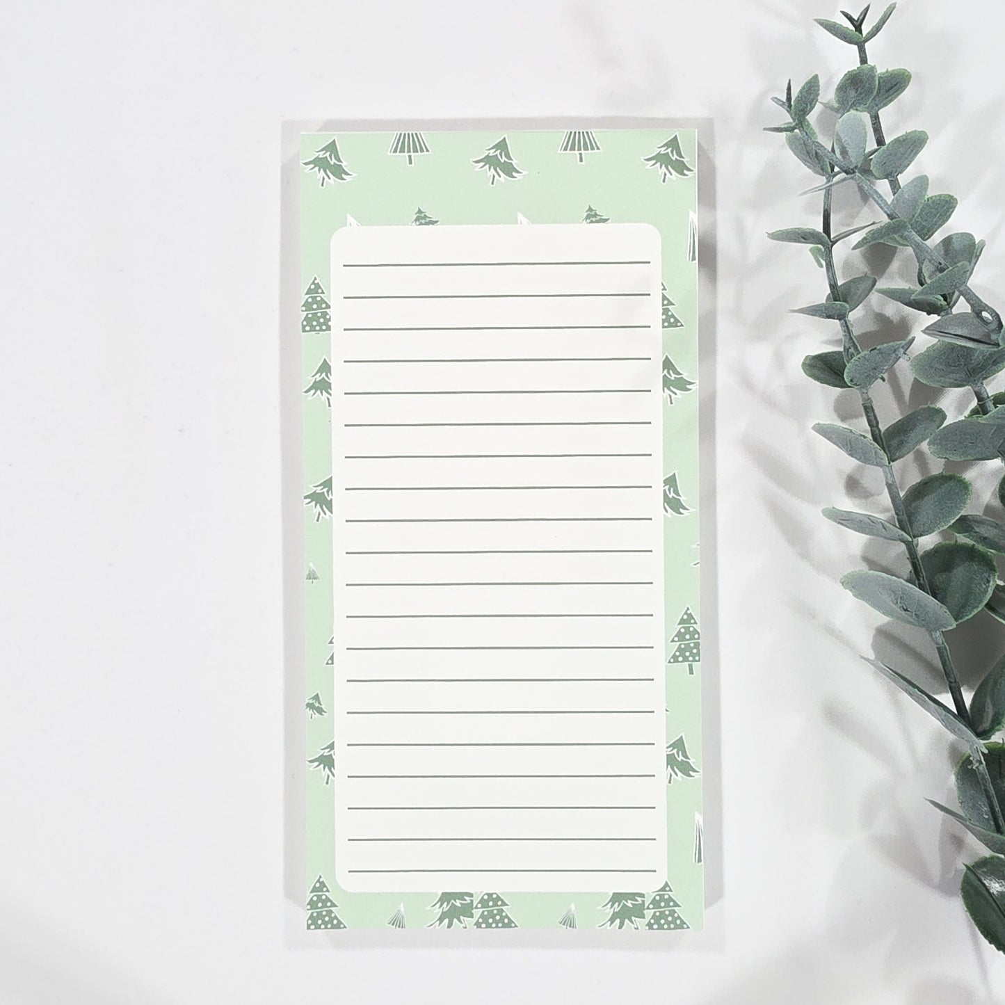 Notepad with green christmas tree border on a white background
