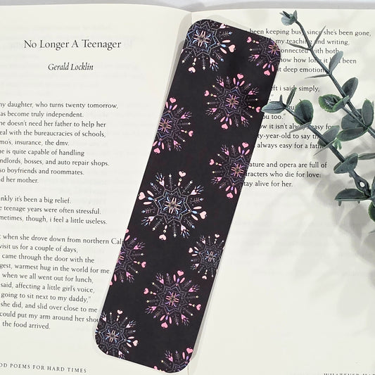 Black bookmark with pink heart patterns on a book page