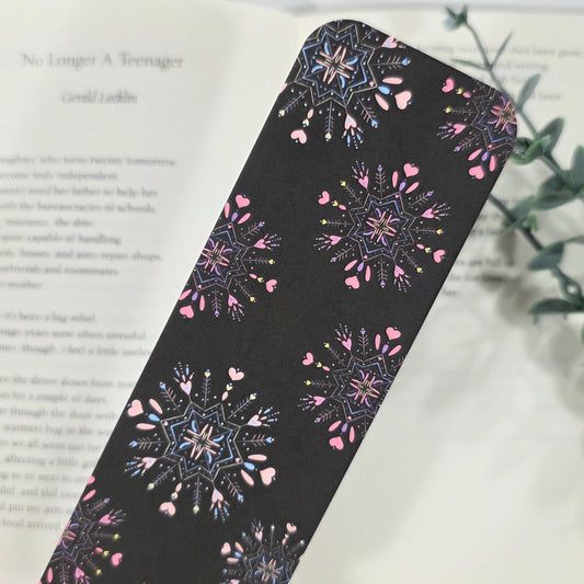 Decorative black bookmark with snowflake pattern on a book page.