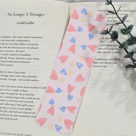 Heart-patterned bookmark on an open book with a plant in the background