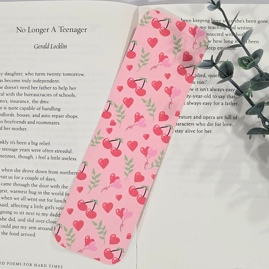 Pink bookmark with heart and cherry pattern on a book page