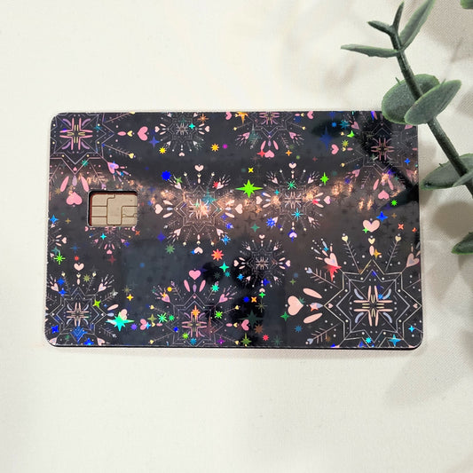 Decorative credit card skin sticker with colorful patterns on an all black background, sitting on a white surface.