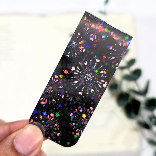 Colorful snowflake pattern on a black background held by a hand with a blurred background