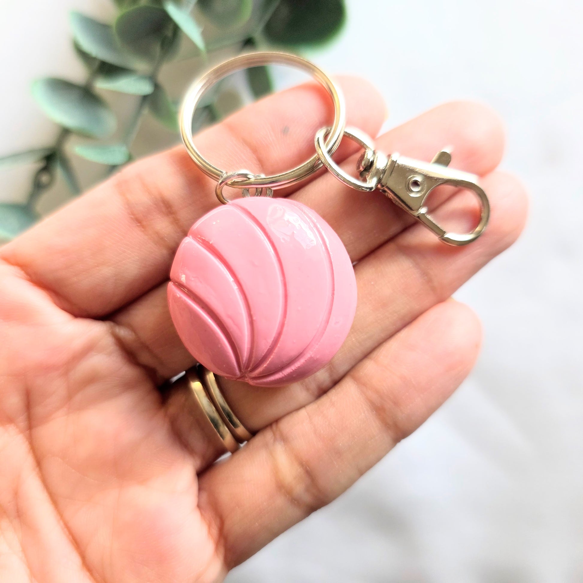 Pink keychain with a metal clip held in a hand against a blurred background