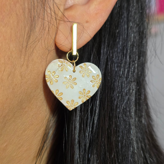 Heart-shaped hair clip with gold floral design worn on a person's hair.
