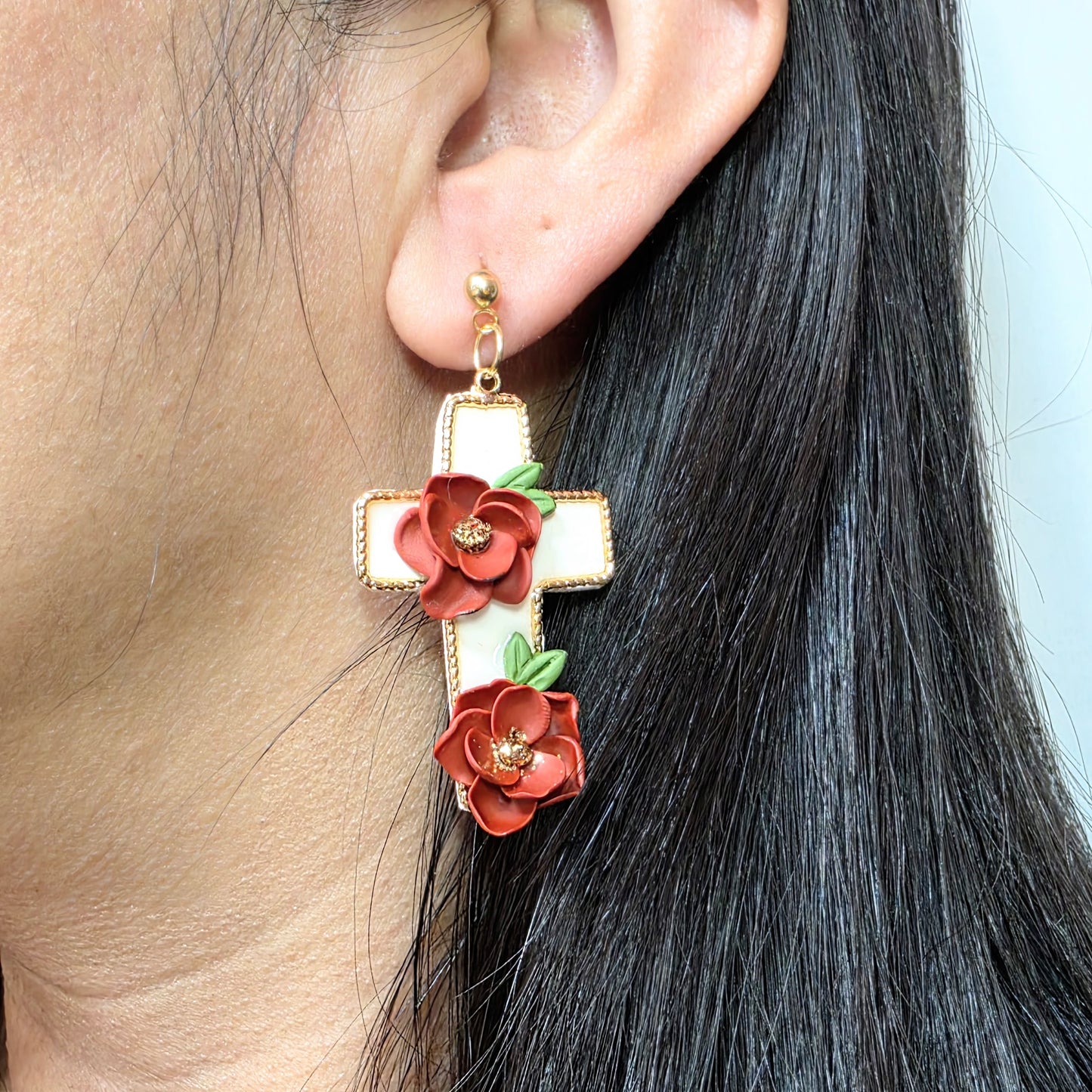 Earring with floral design worn by a person with black hair.