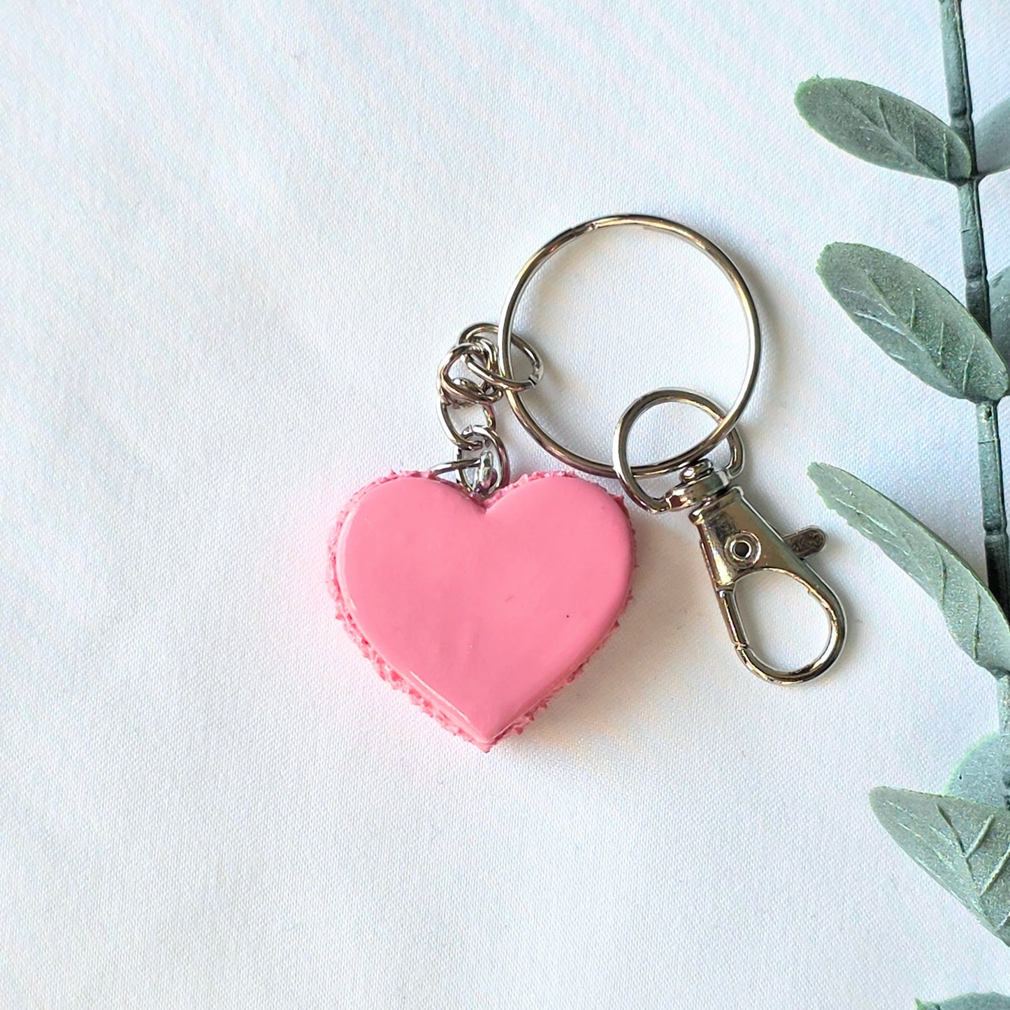 Pink heart-shaped keychain with a plant on a white background