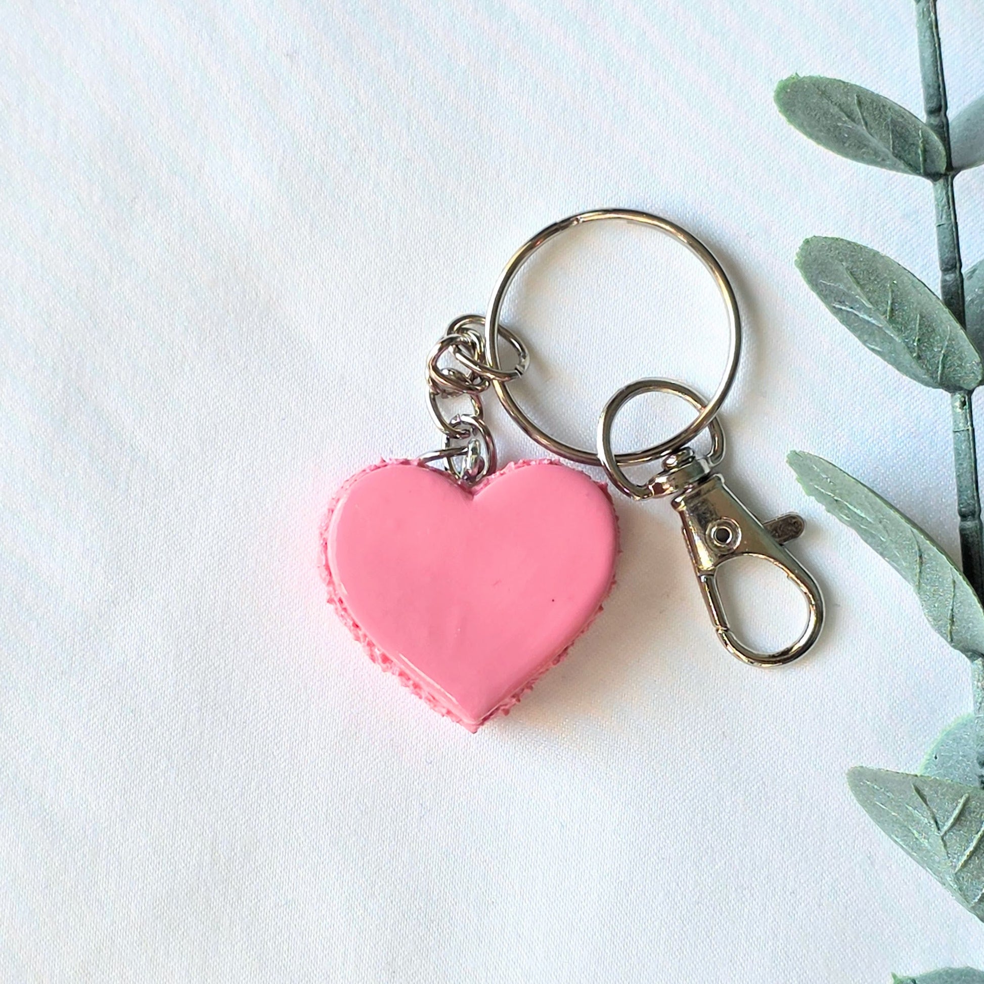 Pink heart-shaped keychain with a plant on a white background