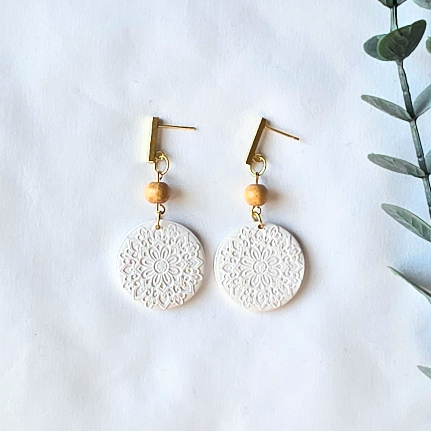 White lace-style earrings with wooden beads on a white background