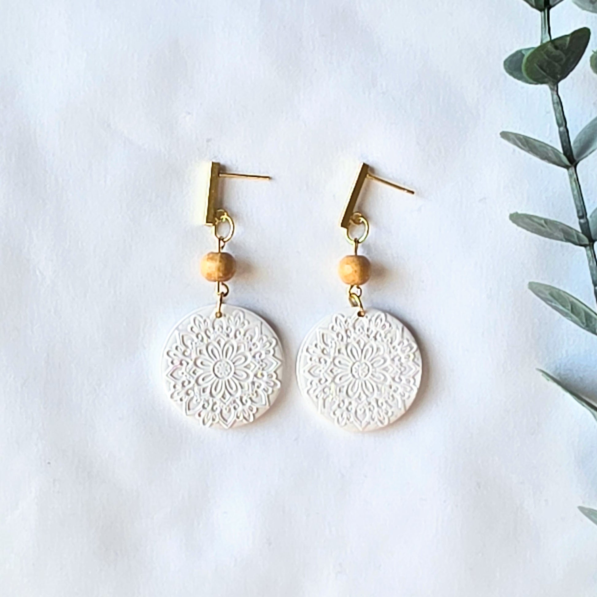 White lace-style earrings with wooden beads on a white background
