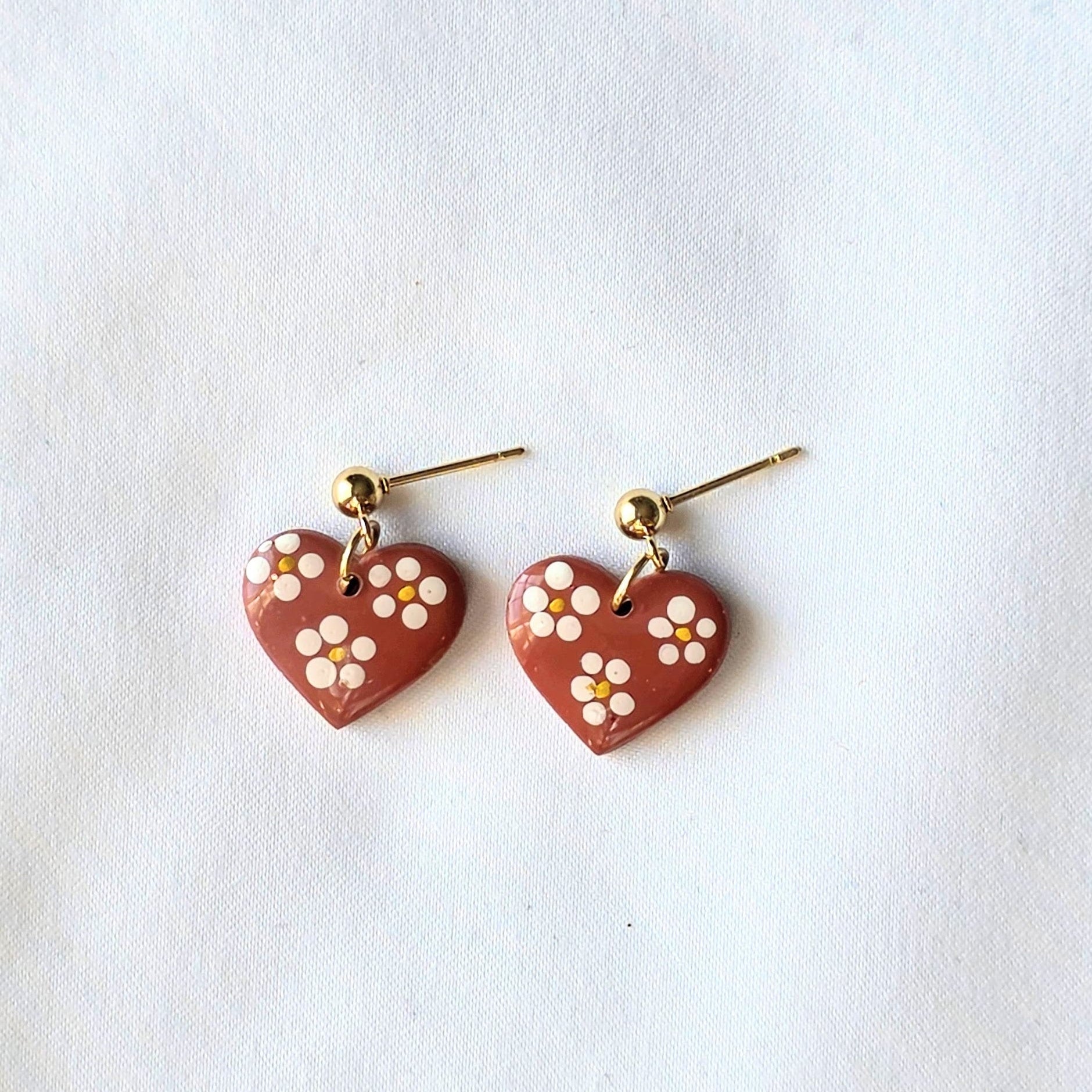 Heart-shaped earrings with floral designs on a white background