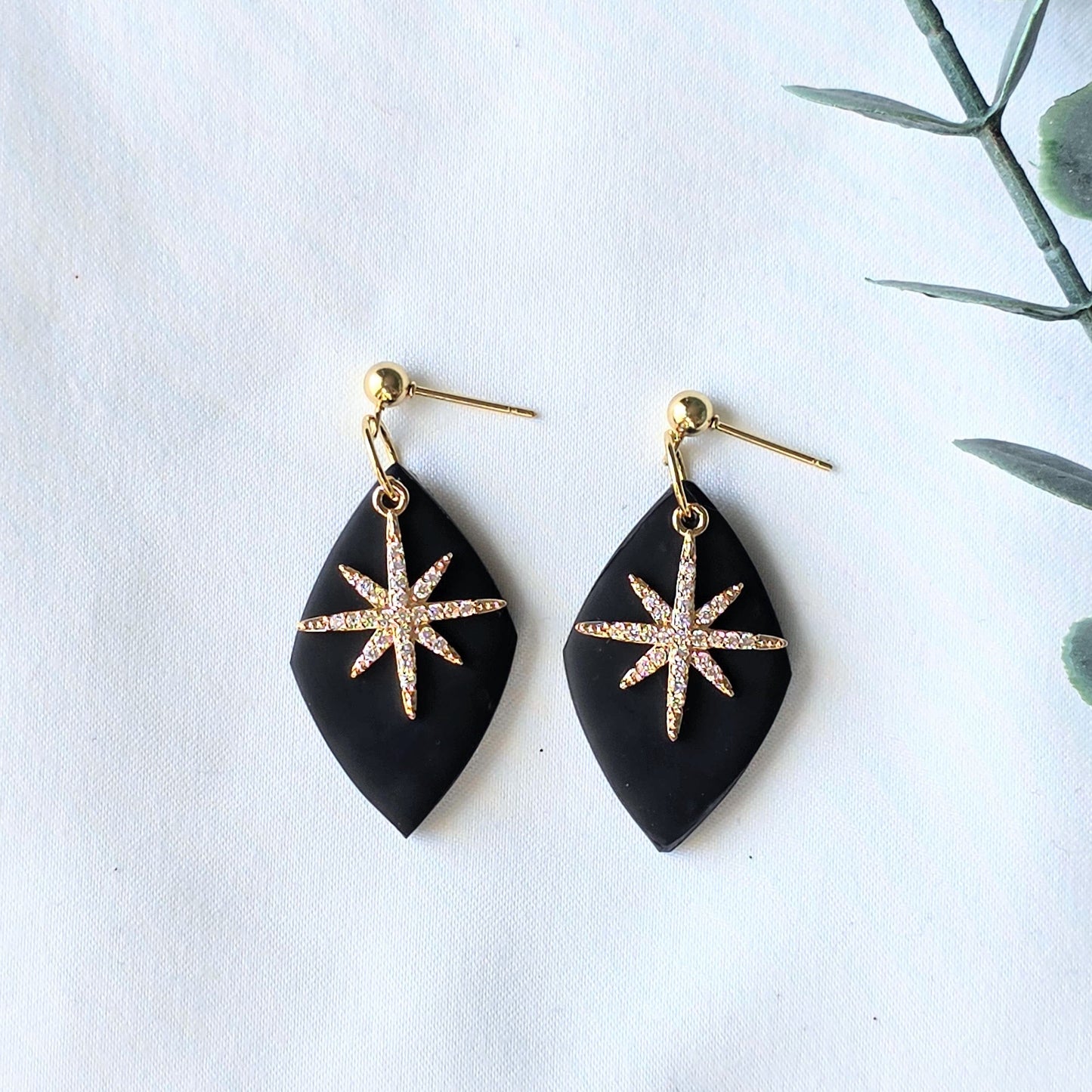 Black earrings with gold star designs on a white background
