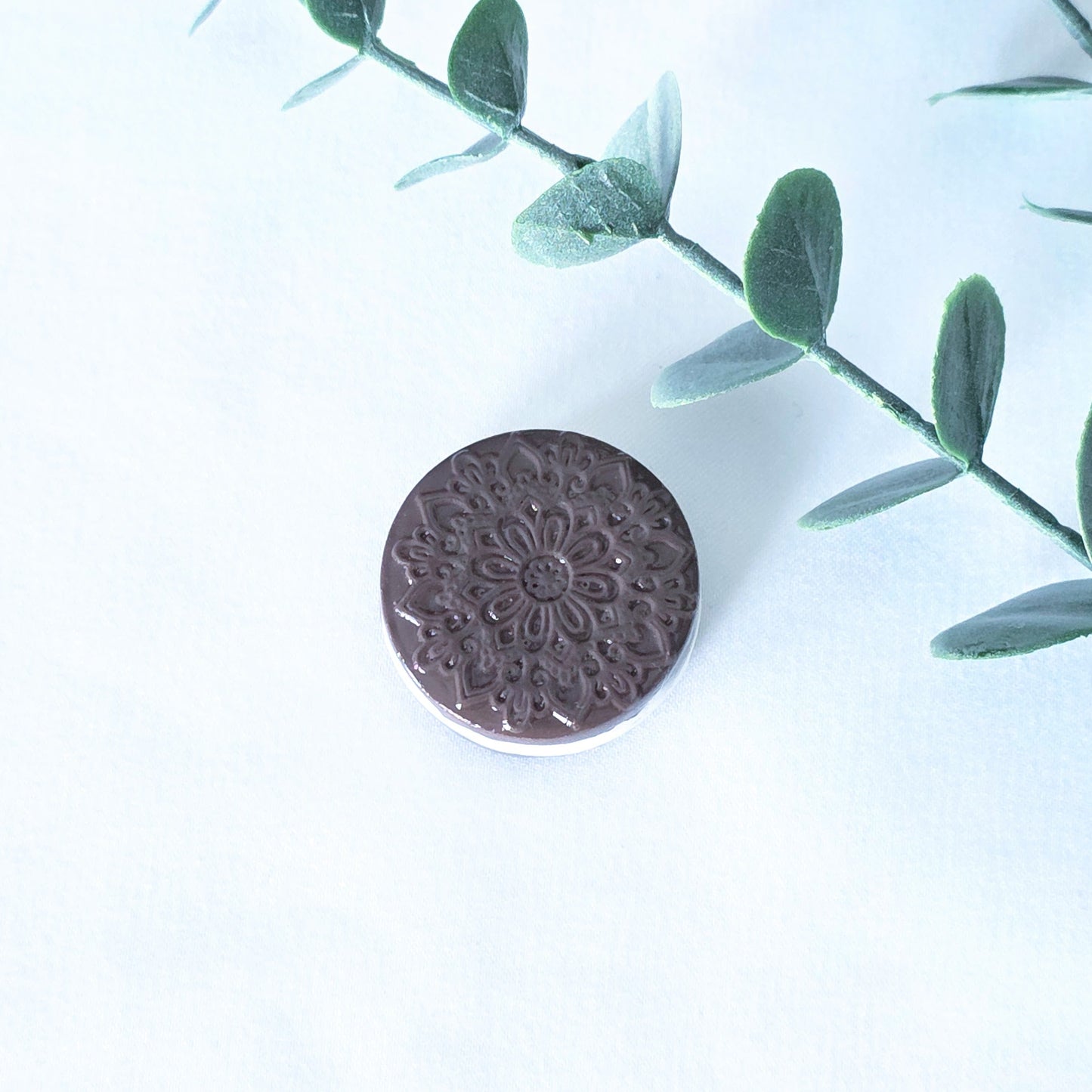 Polymer clay cookie with floral pattern on a white background with green leaves.