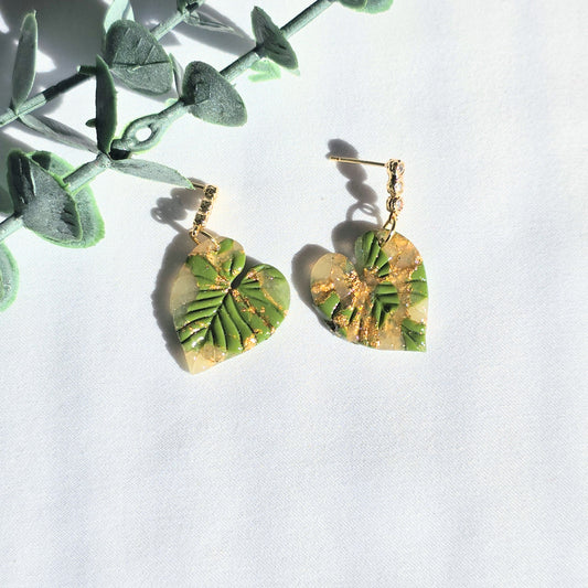 Green leaf-shaped earrings with gold accents on a white background