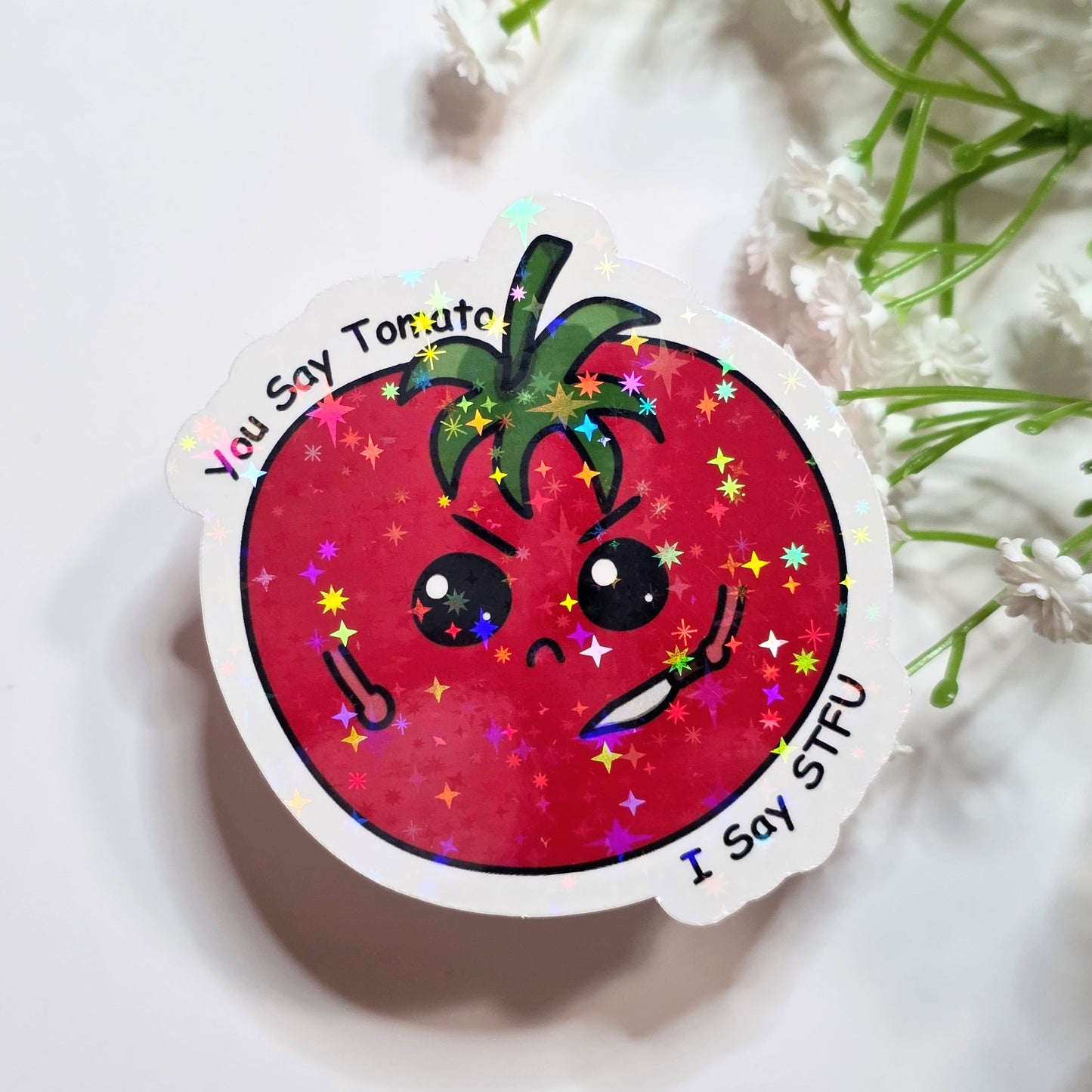 Sticker with a cartoon tomato face on a white background with greenery